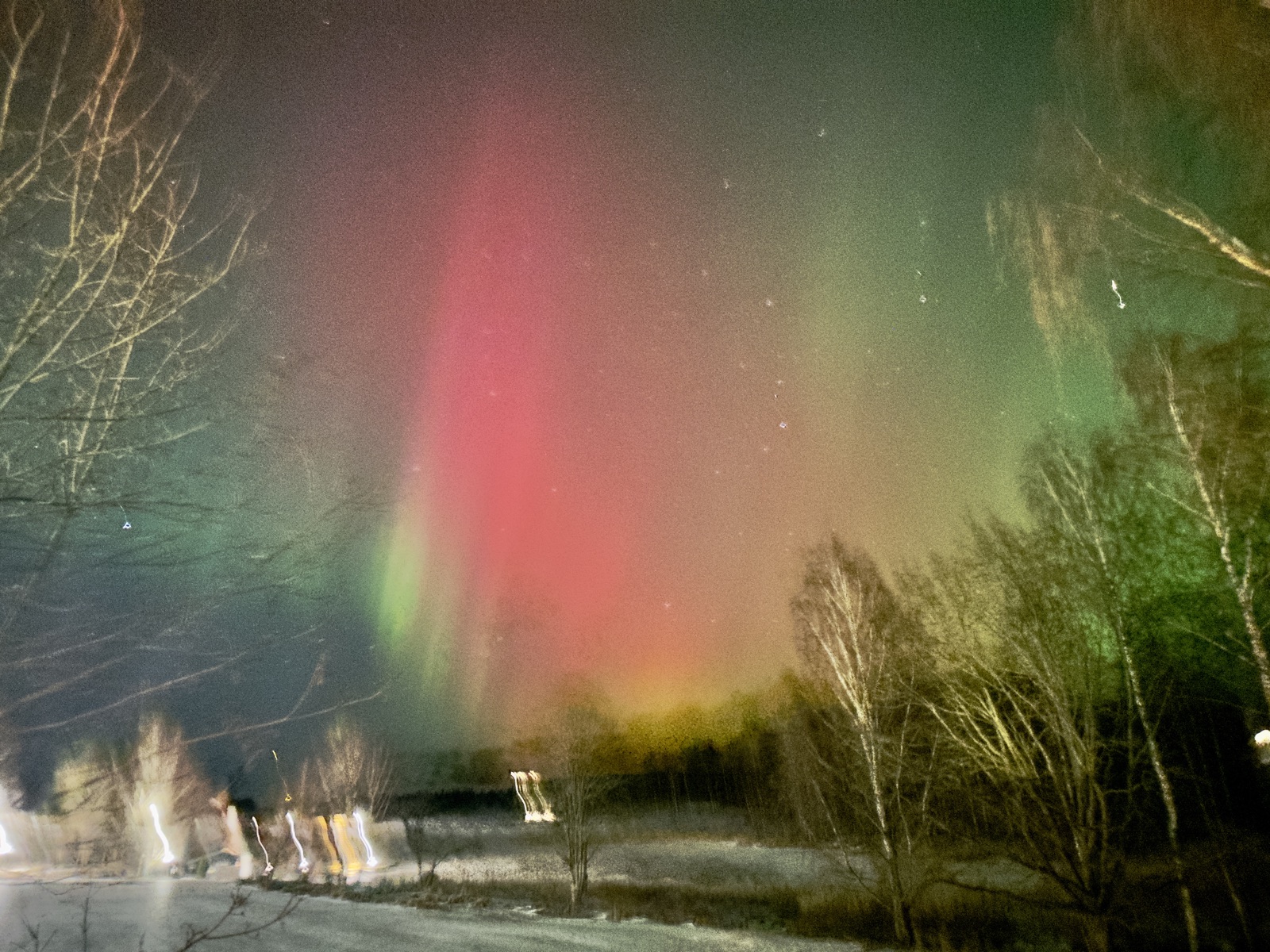 Red green aurora borealis pillars blazing over frozen Finnish lake Ruka